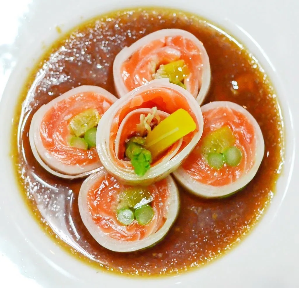 Salmon rolls arranged as a flower in ponzu sauce