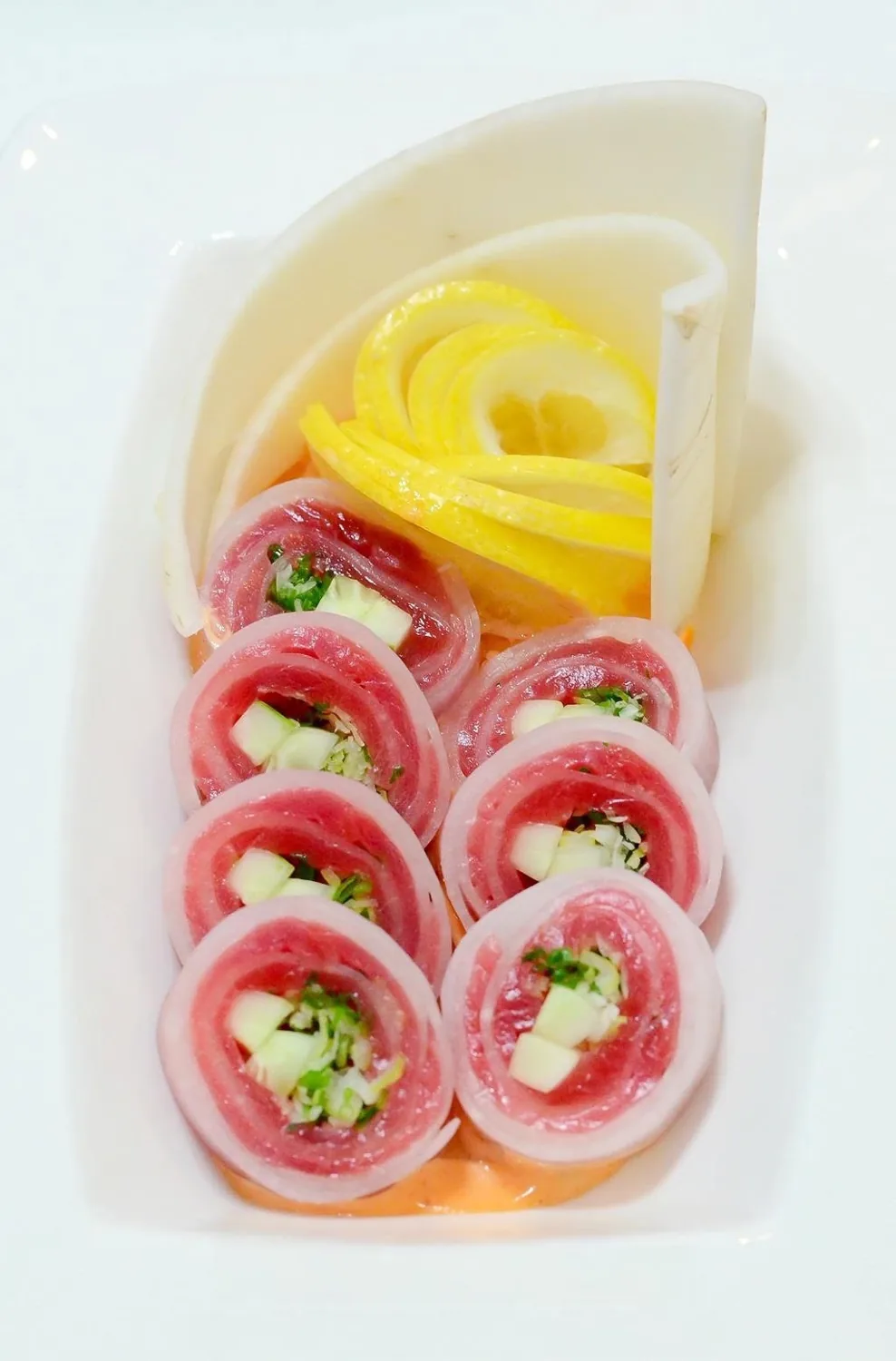 Tuna rolls with lemon on a white plate